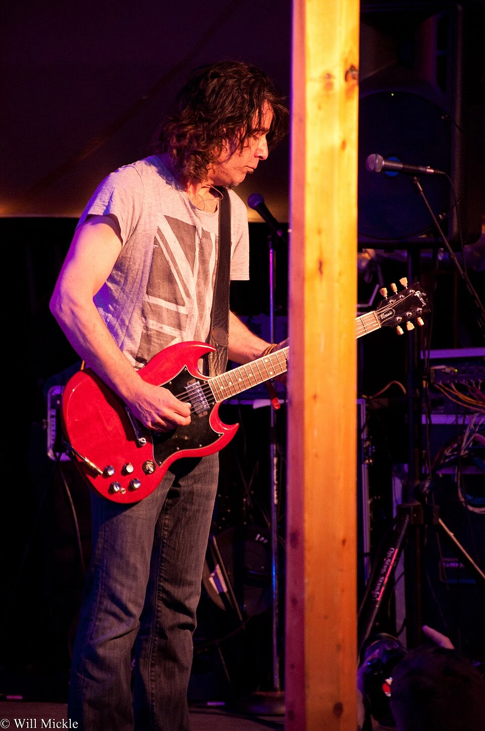 Eric Schenkman performing on stage with a red guitar