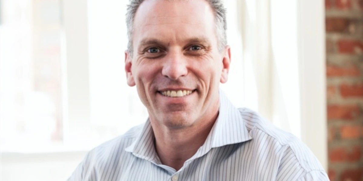 Greg Schott smiling in a bright office portrait