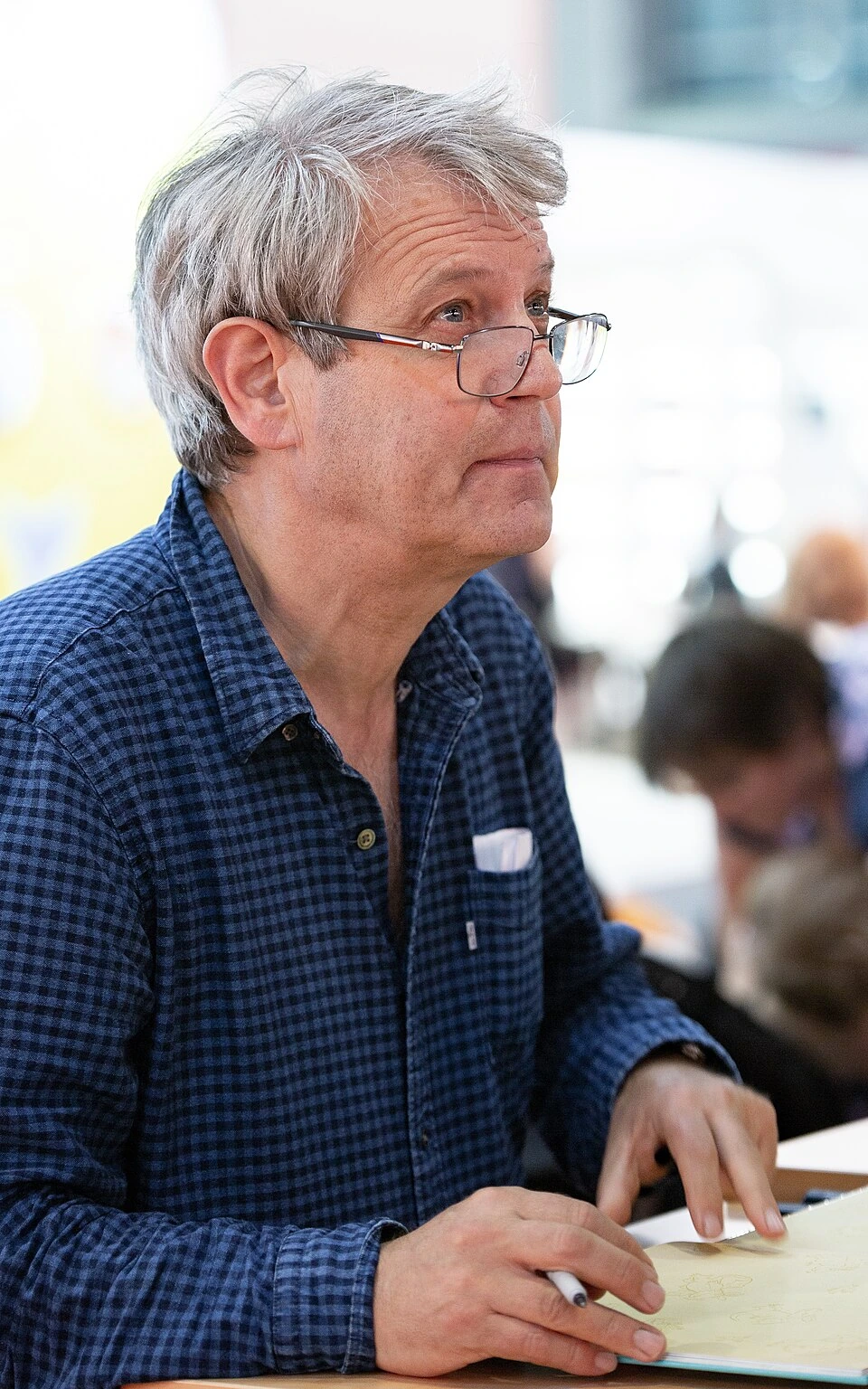 Axel Scheffler at an event, holding a pen while signing or drawing.