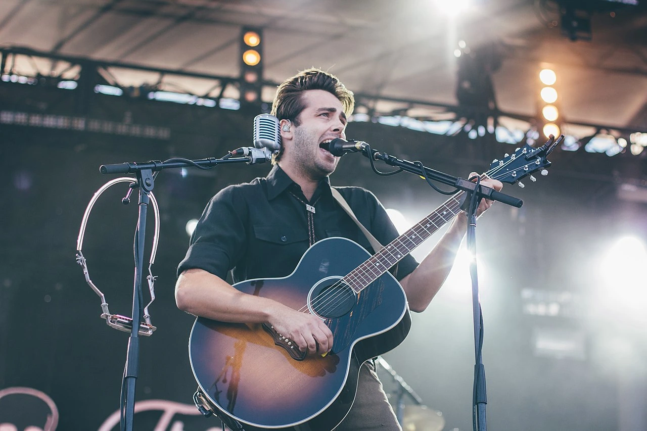 Benjamin E. Schneider performing on stage with a guitar